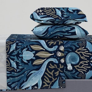 Op de afbeelding: Een blauwe en witte beddengoedset met een zeeleven-patroon. Het patroon bevat zeedieren zoals vissen, zeepaardjes en zeeschildpadden. De beddengoedset bevat een plat laken, een hoeslaken en twee kussenslopen.
