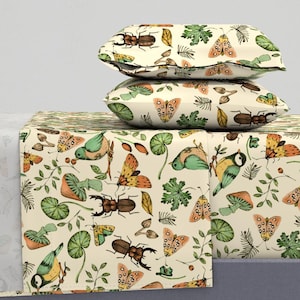 Könnte beinhalten: Ein cremefarbenes Bettwäsche-Set mit einem verspielten Muster aus Schmetterlingen, Vögeln, Käfern und Pilzen. Das Bettwäsche-Set beinhaltet ein Spannbettlaken, ein flaches Laken und zwei Kissenbezüge.