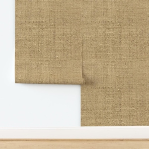 May include: A close-up of a brown burlap fabric with a subtle woven texture. The fabric is folded over on itself, revealing the underside.