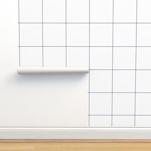 May include: A white wall with a roll of navy blue grid wallpaper partially applied. The wallpaper has a grid pattern with thin lines.