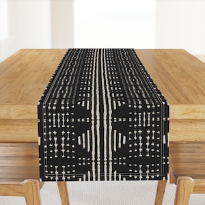 May include: Black and white geometric patterned table runner. The runner has a modern design with vertical lines and dots.