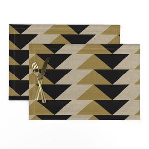 May include: Set of two placemats with a geometric pattern of black and gold triangles on a beige background.