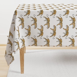 May include: White tablecloth with a repeating pattern of brown and orange tigers. The tigers are facing left and right, and their tails are curled up.