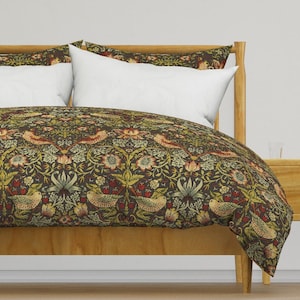Op de afbeelding: Een donkergroene dekbedovertrek met een bloemenpatroon met vogels en bladeren. Het dekbedovertrek ligt op een houten bedframe met twee witte kussenslopen.