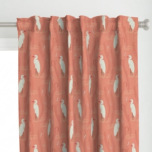 May include: A coral pink curtain with a white egret bird pattern. The birds are standing in a pond with reeds.