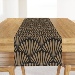 May include: A black and gold table runner with a geometric pattern of overlapping fan shapes. The runner is made of a soft, durable fabric and is perfect for adding a touch of elegance to any dining table.