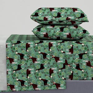 May include: A green and white patterned bed sheet set with a repeating pattern of okapi animals. The set includes a flat sheet, fitted sheet, and two pillowcases.