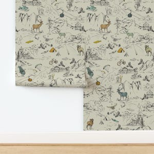 May include: Wallpaper roll featuring a repeating pattern of a mountain landscape with deer, bears, tents, and ski lifts. The design includes black line drawings with touches of yellow and blue on a neutral background.