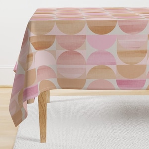 May include: A pink and brown geometric tablecloth with a repeating pattern of semi-circles. The tablecloth is made of a soft, woven fabric and has a subtle sheen.