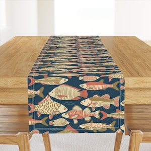 May include: A blue table runner with a repeating pattern of colorful fish. The fish are in various shades of red, orange, yellow, and brown. The runner is perfect for adding a touch of whimsy to any dining table.