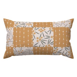 Puede incluir: Cojín decorativo rectangular con diseño de patchwork. El cojín presenta un patrón de cuadrados amarillo mostaza y blancos. Algunos cuadrados tienen un diseño floral con flores amarillas y hojas verdes. Otros cuadrados tienen un patrón de puntos.