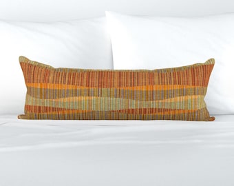 May include: A long, rectangular throw pillow with a woven pattern in shades of orange, brown, and green. The pillow is made of a soft, textured fabric.