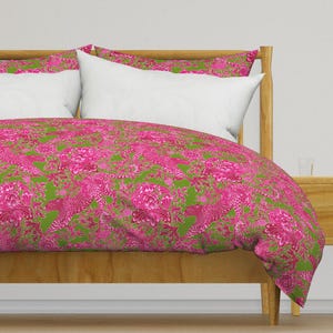 May include: A green and pink patterned duvet cover with a floral and bird design. The duvet cover is on a wooden bed frame.