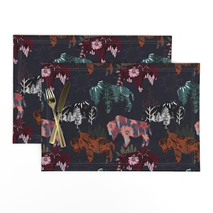 May include: Two dark blue placemats with a repeating pattern of stylized bison, trees, and flowers in shades of red, orange, green, and pink.