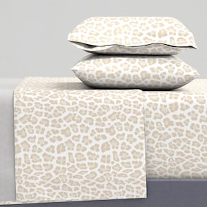 Könnte beinhalten: Ein Bettwäsche-Set in Weiß und Beige mit Leopardenmuster, bestehend aus einem Spannbettlaken, einem Bettlaken und zwei Kissenbezügen.