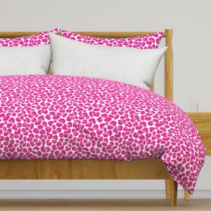 May include: A pink and white leopard print duvet cover with a wooden bed frame.