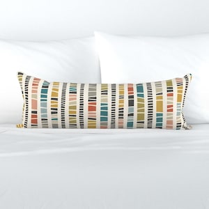 May include: A long rectangular lumbar pillow featuring a repeating vertical pattern of thin black lines and solid color blocks in shades of mustard yellow, teal, terracotta, light pink, and gray on a cream-colored background fabric.