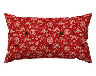 May include: Red cushion with a gold and white pattern of cherry blossoms and Chinese characters. The cushion is rectangular and has a soft, plush texture.