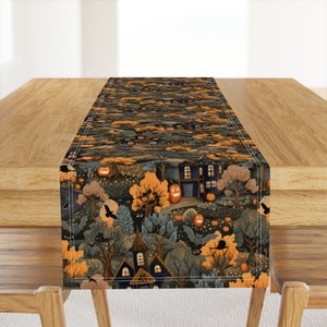 May include: A Halloween-themed table runner with a dark background featuring a repeating pattern of houses, trees, pumpkins, and bats. The runner is decorated with orange, yellow, and black colors.