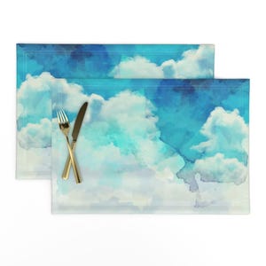 Könnte beinhalten: Zwei blaue und weiße Platzsets aus Stoff mit einem Wolkenmuster. Die Platzsets haben eine dezente Textur.
