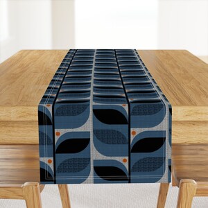 May include: A blue and black geometric table runner with orange circles. The runner has a repeating pattern of stylized leaves.