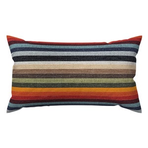 May include: A rectangular throw pillow with a striped pattern in shades of red, orange, yellow, green, brown, blue, and black.