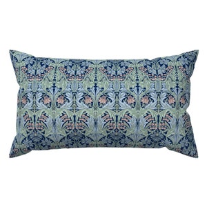 May include: A rectangular pillow with a navy blue background and a repeating pattern of light blue and green floral designs. The floral pattern features pink flowers and leaves.
