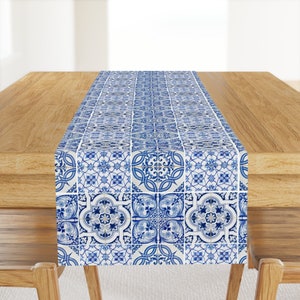 May include: A blue and white table runner with a geometric tile pattern. The runner is made of fabric and has a smooth texture.