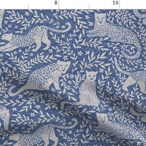 May include: A seamless pattern featuring white leopards and leafy branches on a blue background. The pattern is perfect for fabric, wallpaper, or wrapping paper.
