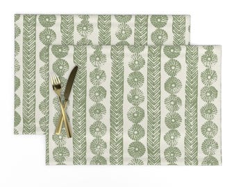 May include: Two green and white placemats with a geometric pattern of circles and stripes. The placemats are made of a linen-like fabric.