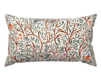 May include: Rectangular decorative pillow with a cream background and a repeating pattern of stylized trees and foliage. The design features brown branches, green leaves, and small flowers in shades of orange, blue, and pink. The pillow is a decorative home accent.