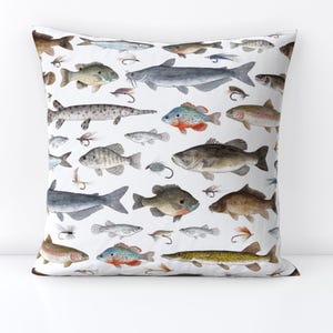 May include: A white cushion featuring a colourful pattern of different fish species, such as bass, catfish, and trout. The cushion is ideal for adding a touch of nature to any room.