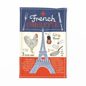 May include: A blue and white kitchen towel with an illustration of the Eiffel Tower, a rooster, and a frying pan. The text "French Omelette" is written in a stylized font. The recipe includes 3 large eggs, 1 tablespoon of butter, salt and pepper, and a non-stick pan.