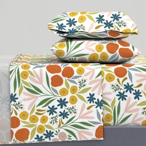 May include: A white bedding set with a floral pattern featuring orange, yellow, and blue flowers. The set includes a fitted sheet, flat sheet, and two pillowcases.