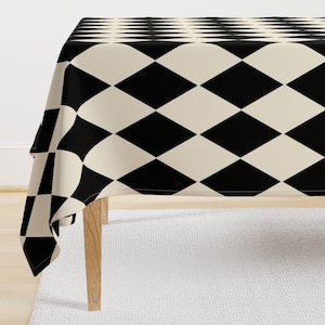 Könnte beinhalten: Tischdecke mit schwarzem und cremefarbenem Diamantenmuster. Die Tischdecke ist über einen Tisch mit Holzbeinen gelegt.
