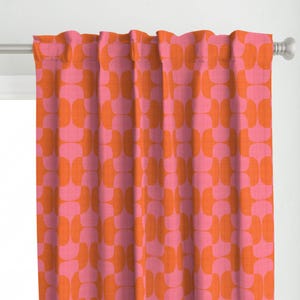 Puede incluir: Cortinas estampadas en rosa y naranja. Las cortinas presentan un diseño geométrico repetitivo de cuadrados redondeados. La tela está drapeada sobre una barra de cortina plateada. La combinación de colores es vibrante.