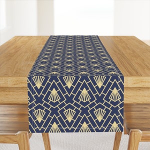 Peut inclure: Un chemin de table bleu marine avec un motif géométrique doré. Le motif présente un dessin répétitif de triangles et d'éventails qui se chevauchent.