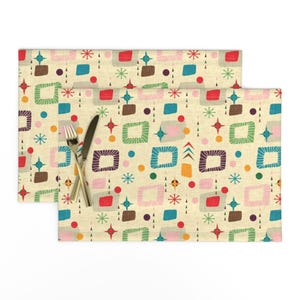 May include: Two beige placemats with a retro mid-century modern geometric pattern in shades of red, green, blue, yellow, pink, brown, and white.