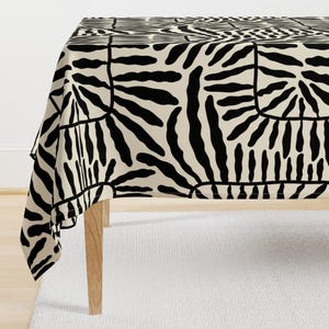May include: A black and cream tablecloth with a geometric pattern. The tablecloth is made of a soft, durable fabric and is perfect for adding a touch of style to any dining table.