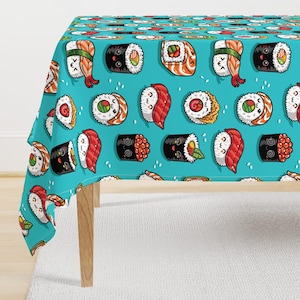 May include: A turquoise tablecloth with a repeating pattern of illustrated sushi rolls. The sushi includes salmon, shrimp, and other ingredients. The tablecloth is draped over a wooden table, with a white rug visible beneath.