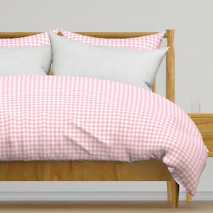 May include: Pink and white gingham duvet cover on a wooden bed frame.