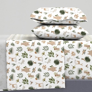 Pode incluir: Conjunto de roupa de cama branco com um padrão repetido de animais da floresta, árvores e folhas em tons de castanho, verde e bege. O conjunto inclui duas almofadas e um lençol com elástico. O tema geral é um design inspirado na natureza.