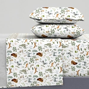 May include: White bedding with a woodland animal print featuring foxes, deer, raccoons, and bears. The print is in shades of brown, green, and gray on a white background.