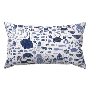 May include: A white pillow with a blue and white pattern of various sea creatures, including fish, jellyfish, crabs, and starfish.