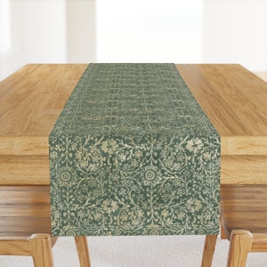 May include: A green table runner with a white floral pattern. The runner is on a wooden table.