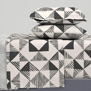 May include: A white and black geometric patterned bedding set with two pillowcases. The pattern features black lines and triangles on a white background.