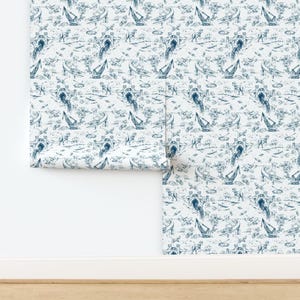 May include: Wallpaper roll featuring a repeating pattern of blue illustrations on a white background. The design includes boats, airplanes, bridges, and figures. The wallpaper is partially unrolled, revealing the pattern.