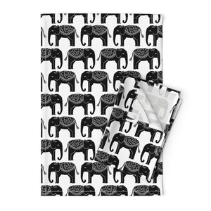 May include: Black and white kitchen towel with a repeating pattern of stylized elephants. The elephants have intricate designs on their backs.
