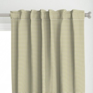 Puede incluir: Un par de cortinas con estampado de cuadros vichy en verde oliva y blanco. Las cortinas cuelgan de una barra plateada y tienen un diseño clásico de estilo campestre. La tela es un material suave y tejido.