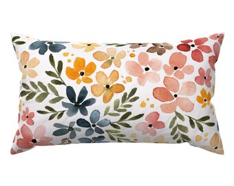 Peut inclure: Un coussin rectangulaire avec un fond blanc et un motif floral. Les fleurs sont dans des tons de rose, orange, jaune et bleu, et elles sont peintes dans un style aquarelle.